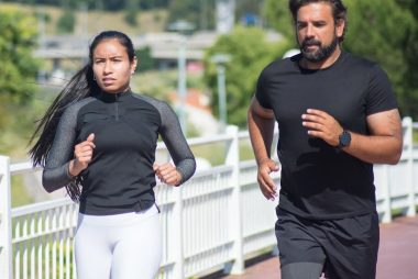 Active couple jogging outdoors on a sunny day, promoting fitness and healthy lifestyle.